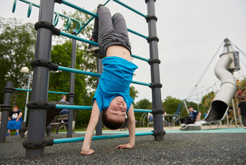 A boy is hanging upside down on a children's playground
