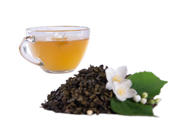 Dried tea leaves, fresh jasmine blossoms with green leaf and translucent glass tea cup showcased in...
