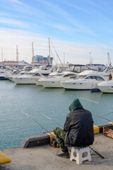 Fisherman at the seaport at the yacht parking lot in Sochi, Russia, in winter