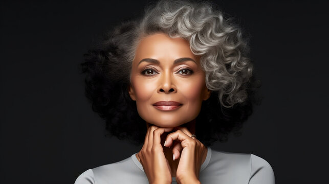Portrait of middle aged black woman on isolated grey background, mature skin makeup and skincare