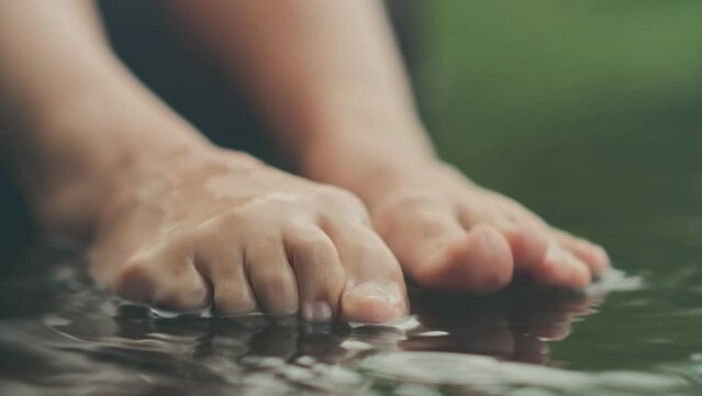 female feet touch the surface of the water