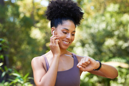 Beautiful multi-ethnic woman gets ready for trail run in forest, earphones watch
