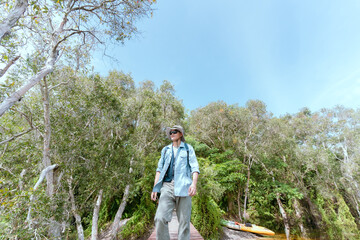 Asian man taking a walk on a bridge river and mangrove forest