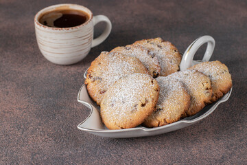 Homemade shortbread cookies with raisins as well cup of coffee on a brown background, Closeup