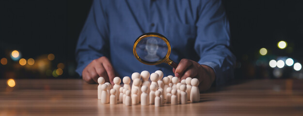 Businessman holding magnifier glass focus to wooden doll, Human development recruitment leadership...