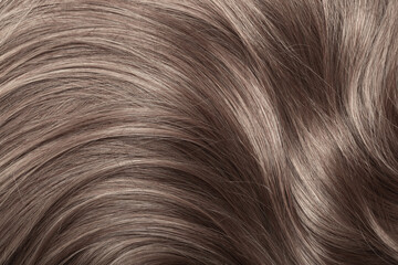 Blond hair close-up as a background. Women's long light brown hair. Beautifully styled wavy shiny...