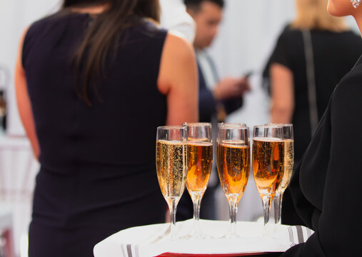 gros plan sur des verres &agrave; champagnes pleins sur un plateau de service &agrave; l'ext&eacute;rieur dans les mains d'une serveuse lors d'un &eacute;v&eacute;nement chic