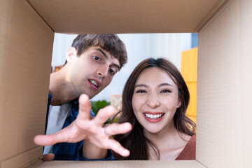 Young mixed race couple open up gift box and reach their hand to taking gift outside of the parcel...