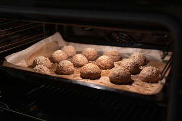Homemade diet buckwheat flour buns sprinkled with sesame are in the oven. Proper...