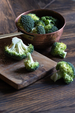 Broccoli cabage cutted on wooden board and put to vintage colander on dark wooden background