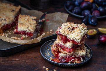 Juicy plum pie slices with streusel topping on rustic wooden background