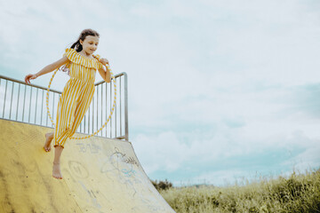 Mädchen, 9 Jahre, im gelbweiß gestreiften Jumpsuit turnt mit gestreiften Hula-Hoop-Reifen
