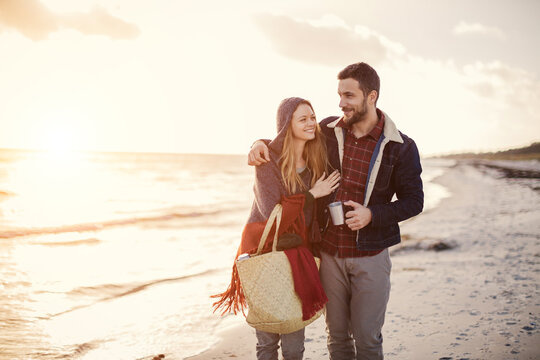 Young couple walking on a beach during winter at sunset