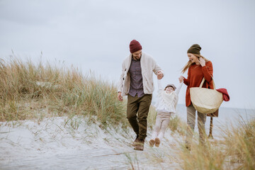 Young family walking on a beach during winter - Powered by Adobe