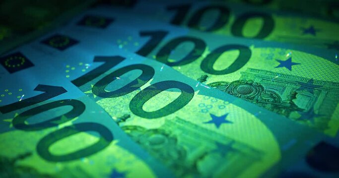 100 Euro banknotes under UV light. Security signs and elements on real euro banknotes glow under ultraviolet light