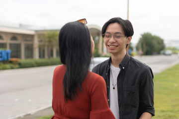 A young affectionate asian couple enjoy a nice chat while looking at each other's eyes and smiling. A public display of affection.