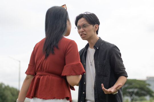 A Young Asian Couple Having A Heated And Vocal Conversation Outside A Public Area. A Tense And Toxic Relationship Between Two Assertive And Unyielding People In A Bitter Power Struggle.