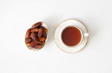 Tea and dried dates on a white background. Natural oriental sweets. Healthy breakfast. View from above.
