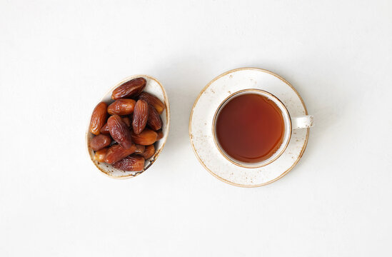 Tea and dried dates on a white background. Natural oriental sweets. Healthy breakfast. View from above.
