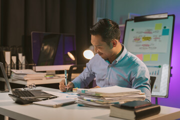 Naklejka premium Young Asian businessman talking on the phone late night hustle ambitious Working overtime talking on the phone in the organization