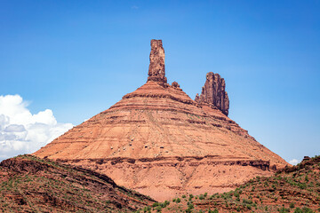 Red sandstone spires formation on a butte in the southwest desert landscape of Utah with blue sky.
