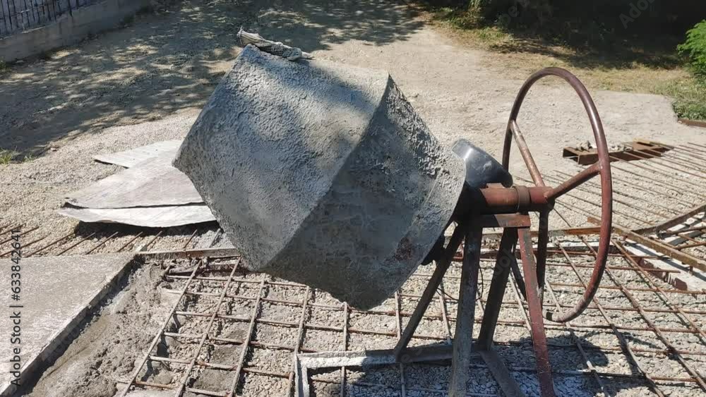 Poster manual concrete mixer at a construction site in summer.