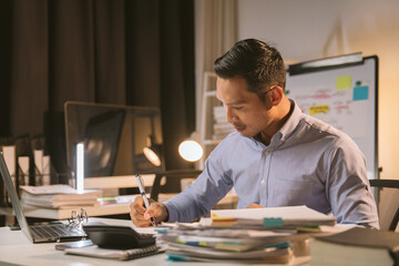 Naklejka premium Young Asian businessman talking on the phone late night hustle ambitious Working overtime talking on the phone in the organization
