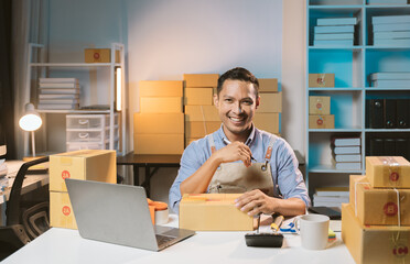 Asian male small business owner using mobile app on smartphone checking parcel box. Warehouse...