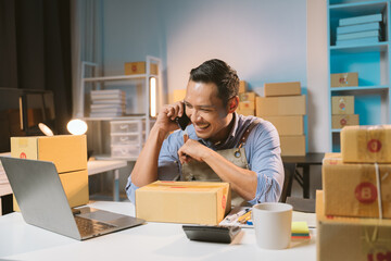 Asian male small business owner using mobile app on smartphone checking parcel box. Warehouse...