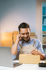 Asian male small business owner using mobile app on smartphone checking parcel box. Warehouse...