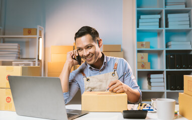Asian male small business owner using mobile app on smartphone checking parcel box. Warehouse...
