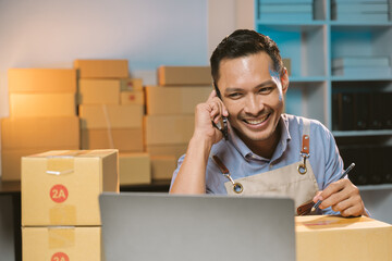 Asian male small business owner using mobile app on smartphone checking parcel box. Warehouse...