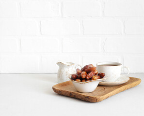 Dried dates in a bowl, tea in a wooden tray on white background. Healthy breakfast. Natural oriental sweets. Copy space.