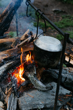 Cooking on the fire for a camping trip. Pot over a fire outdoors. The romance of the wild tourism and food in camp. Backpacking on the nature at sunset.