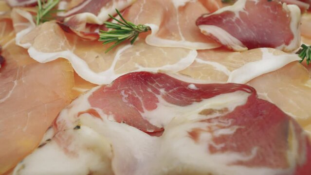 Cured pork meat with mozzarella, tomatoes, and fresh rosemary. Slices of raw ham, close up