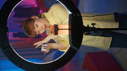 Fototapeta premium Young girl talking about the new perfume in front of the camera at home studio. Vertical photo