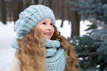 Portrait of cute little child, beautiful kid girl in hat and scarf at cold winter snowy day walk in...