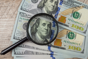 dollars are visible through a magnifying glass.