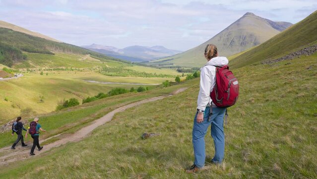 Backpacking trekker looking at picturesque view of the Scottish Highland landscape with grassy meadows and hills. West Highland Way, Scotland
