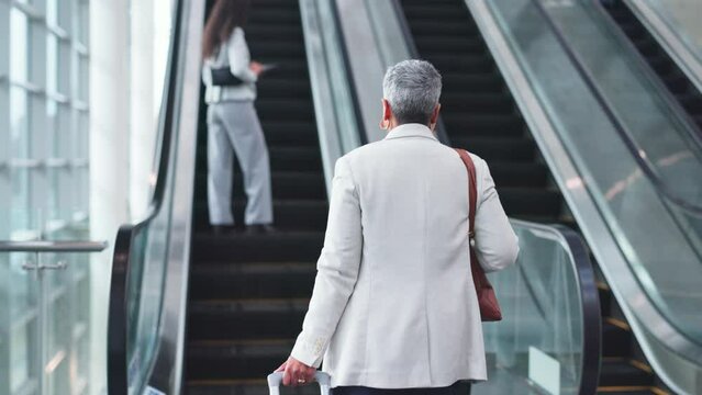 Escalator, airport and business woman with luggage for commute, travel and arrival in lobby. Modern building, professional and back of mature person and suitcase on electric stairs for transportation