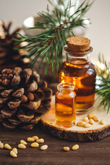 Organic essential oil, pine nuts, cedar cone on rustic wooden dark background. Concept of natural ingredients, naturopathy, herbal extracts and essence. Alternative medicine, aromatherapy