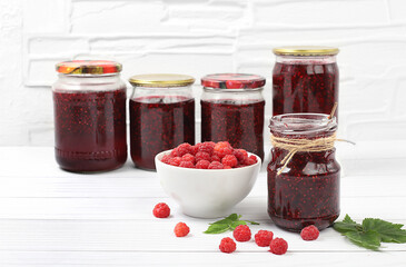 Jars of raspberry jam on a light wooden background with leaves, banner and shop advertisement,...
