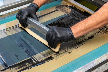 Fototapeta na wymiar hand made screen printing, squeezing the paint with a squeegee