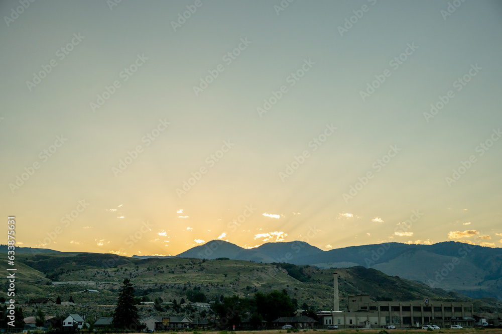 Sticker faint sun rays shine over gardiner montana at sun rise