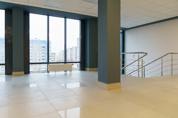 View of an empty spacious hall with columns and panoramic windows. Modern interior design of an empty office. A room with large windows, doors and an elevator.