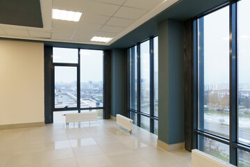 View of an empty spacious hall with columns and panoramic windows. Modern interior design of an empty office. A room with large windows, doors and an elevator.