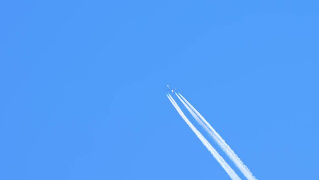 Jet aircraft plane with a bright white contrail at blue sky. Aeroplane vapour, Contrails, Chemtrails, or Condensation Trail, aviation aircraft emissions from engines. CO2 carbon dioxide from plane.