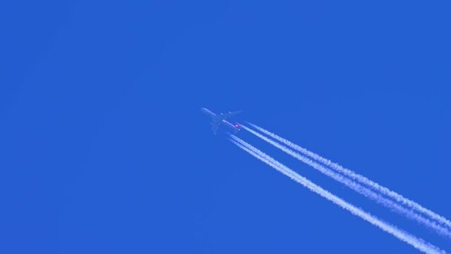 Jet aircraft plane with a bright white contrail at blue sky. Aeroplane vapour, Contrails, Chemtrails, or Condensation Trail, aviation aircraft emissions from engines. CO2 carbon dioxide from plane.