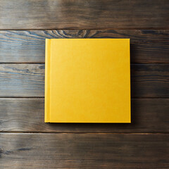 Yellow hardcover photobook isolated on a wooden background with copy space. Top view, flat lay....