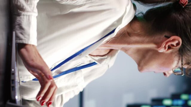 Vertical video Dilligent inspector in cloud computing company headquarters housing high end blade servers capable of efficiently performing complex computations and data analysis, using tablet to